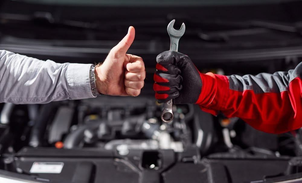 Customer giving a thumbs up to a mechanic holding a wrench