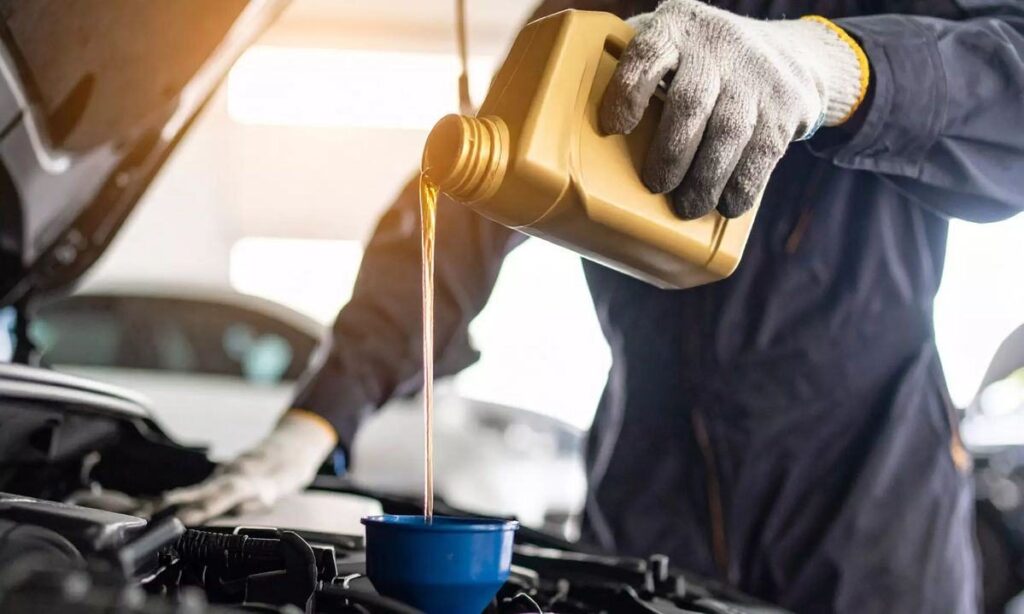 Technician pouring premium motor oil into an engine